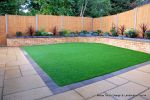 Low maintenance garden constructed with new Saxon paving, Curved planter wall using old stock buff bricks and single bull nose capping, artificial lawn & planting