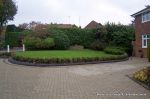 Driveway constructed using pewter grey paving with contrasting colour band and feature curved double row of kerbs with Topiary hedge to retain level change & inset LED lights