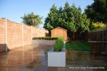 New lawn, planting, shed and fence patio was constructed using fossil sandstone in 4 sizes laid to a random pattern with a curved block planter wall painted in gun ship grey and planted with a topiary hedge.