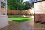 Low maintenance garden constructed with new Saxon paving, Curved planter wall using old stock buff bricks and single bull nose capping, artificial lawn & planting