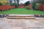 Tired garden received a complete new design Patio installed with 4 size sawn sandstone paving edged with firestone rocks and alpine planting, steps built with sawn sandstone uprights and sawn sandstone bullnose treads, New lawn installed in 3 rings all ed