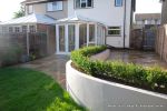 AFTER: New lawn and planting new fence and shed patio was constructed useing fossil sandstone in 4 sizes laid to a random pattern with a curved block planter wall painted in gun ship grey and planted with a topiary hedge.  