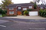 Driveway constructed using pewter grey paving with contrasting colour band and feature curved double row of kerbs with Topiary hedge to retain level change & inset LED lights